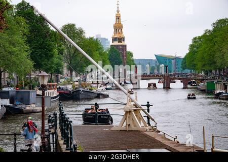 AMSTERDAM, NIEDERLANDE. 06. JUNI 2021. Schöne Aussicht auf Amsterdam mit typisch holländischen Häusern, Brücken und chanel. Kleine Boote auf dem Damm Stockfoto