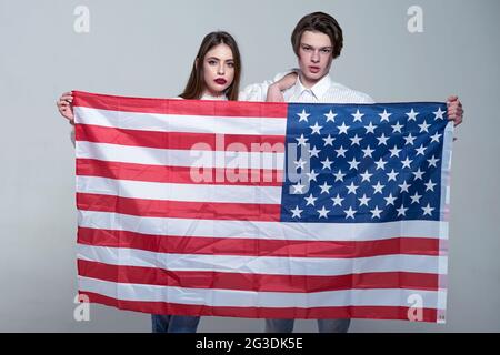 Paar auf ruhige Flächen hält Flagge der USA. Paar begrüßt die USA zu besuchen. Guy und Mädchen stolz, Amerikaner zu sein, grauen Hintergrund. Language School Konzept. Stockfoto