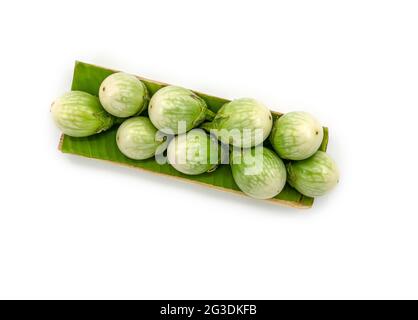 Frische thailändische Auberginen auf einem Bananenblatt mit einem Tablett, das aus einer Banane hergestellt wurde, das Bild auf weißem Hintergrund, Draufsicht thailändische Auberginen. Stockfoto