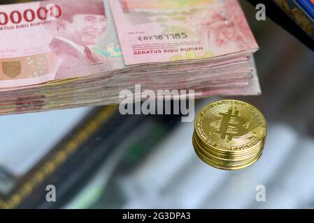 Stapel von hunderttausend Rupiah-Banknoten und Bitcoin, dieses Foto wurde am 15. Juni 2021 in der Stadt Lumajang, Indonesien, aufgenommen Stockfoto