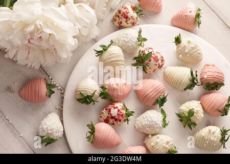 In Schokolade getauchte Erdbeeren auf Marmorplatte auf Holztisch Stockfoto