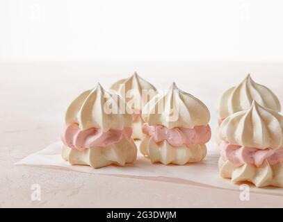 Kleine Baiser-Kuchen aus Eiweiß-Keksen und Erdbeercreme auf rosa Hintergrund Stockfoto