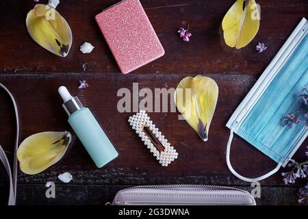 Stilvolle Frauen Kupplung Explosion mit Maske, tropper Glasflasche, Spiegel, Haarnadel von gelben Tulpenblüten umgeben. Draufsicht. Modernes, elegantes feminines Konzept. Stockfoto