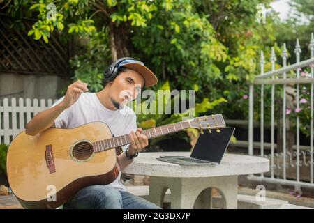 Mann glücklich spielen akustische Gitarre zu Hause Stockfoto