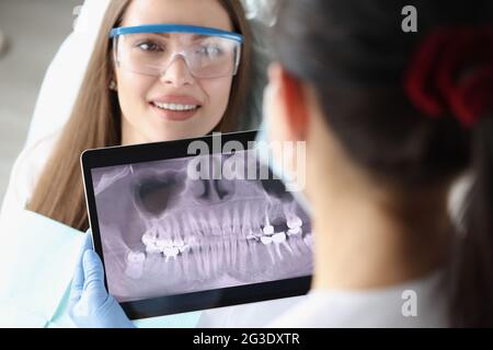Zahnarzt Arzt untersucht Röntgenbild auf Tablet-Bildschirm im Stuhl ist Frau Patientin Stockfoto