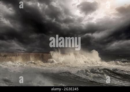 Dramatische Seeszene mit großen weißen Wellen, die gegen die Hafenmauer von Leixoes in der Nähe von Porto in Portugal krachen. Verbesserter Himmel. Stockfoto