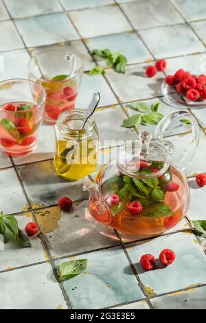 Heißer Himbeer-Tee in transparenter Teekane auf einem Steintisch. Frische Beeren, Minze, Glasbecher Stockfoto