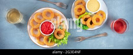 Calamari rings Panorama. Frittierte Tintenfischringe mit grünem Salat, Wein und verschiedenen Saucen, Top-Shot, flaches Lay Stockfoto