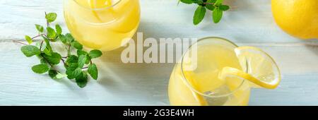 Panorama mit frischen Zitronengetränken. Hausgemachtes Limonade-Panorama-Banner. Erfrischendes Zitrusgetränk mit Minze auf Holzgrund Stockfoto