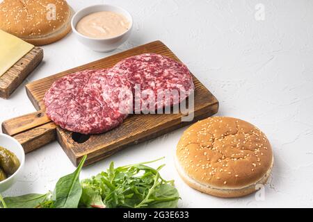 Hausgemachter Hamburger. Hacksteaks, Sesambrötchen mit anderen Zutaten, auf weißem Steingrund, mit Platz für Text Stockfoto