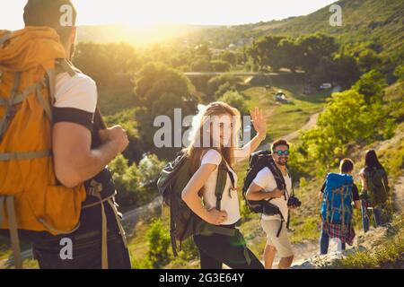 Eine Gruppe von glücklichen Freunden mit Rucksäcken, die im Sommer an sonnigen Tagen den Wanderweg entlang wandern Stockfoto