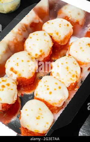 Set von Sushi-Rollen in Lieferkarton, auf schwarzem Steinhintergrund Stockfoto