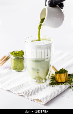 Grünen Matcha-Tee in Eisglas mit Milch gießen Stockfoto