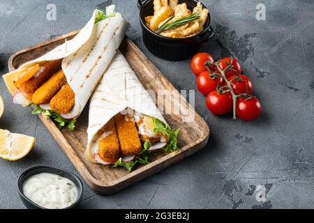 Fischfinger Rollen und Tartar-Sauce-Set, auf Holztablett, auf grauem Hintergrund, mit Copyspace und Platz für Text Stockfoto