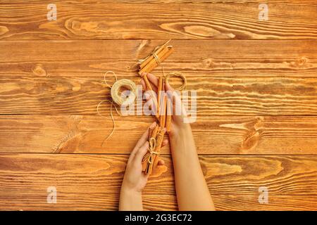 Zimt klebt in den Händen auf einem hölzernen Hintergrund. Garn zum Verpacken von Geschenken. Das Konzept von Thanksgiving und Weihnachten. Flaches Lay einer festlichen Komposition mit Kopierraum. Stockfoto