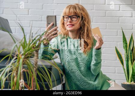 Lächelnde Frau mit Handy und Karte zu Hause Stockfoto