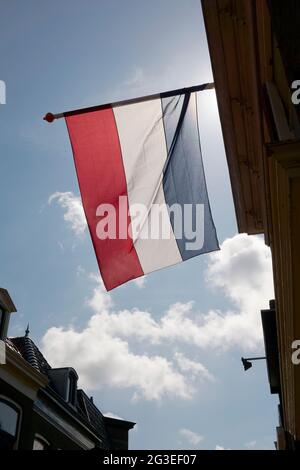 Niederländische Flagge winkt im Wind gegen einen blauen Himmel mit weißen Wolken um den Königstag in den Niederlanden. Ein nationaler Feiertag. Stockfoto