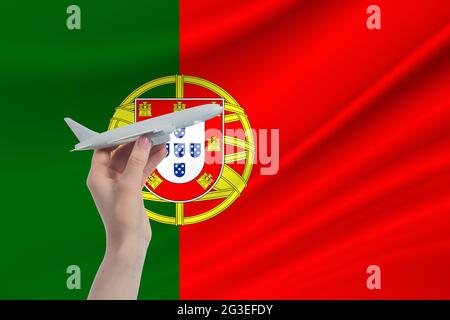 Flugzeug in der Hand mit der Nationalflagge Portugals. Reise nach Portugal. Stockfoto