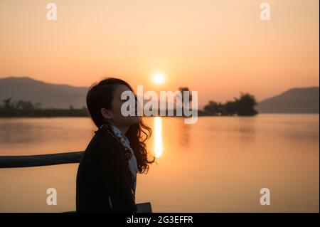 Schöne junge asiatische Frau genießen mit Sonnenaufgang auf Bergsee am Morgen Stockfoto