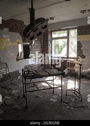 Verlassene Station in einem zerstörten Krankenhaus mit rostigen Geräten und einem kaputten Fenster Stockfoto