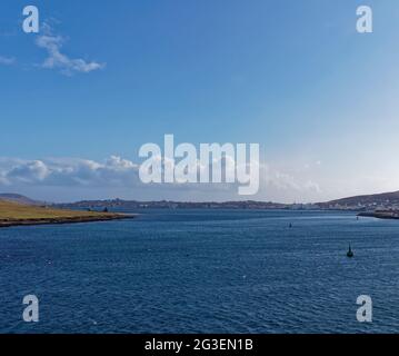 Die Stadt Lerwick in der Ferne, südlich vom Peterson Quay, mit Navigation Booys im Shetland Sound an einem luftigen Tag. Stockfoto