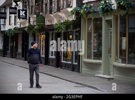 Ein Mann geht allein und schaut in die Fenster geschlossener Geschäfte entlang Stonegate im Zentrum von York, im Norden von Yorkshire. York ist eine Stadt, die vom Tourismus lebt Stockfoto