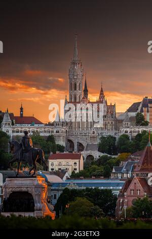 Budapest, Ungarn - St. Matthias Kirche und Fischerbastei (Halaszbastya) mit Statue von Gyula Andrassy im Vordergrund und schönem goldenen Sonnenuntergang Stockfoto