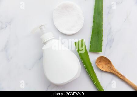 Aloe Vera natürliche Hautpflege weiße Produktflasche mit grünen Blättern. Flache Lay-Komposition Stockfoto