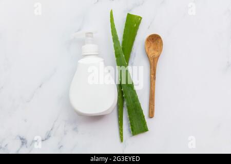 Aloe Vera natürliche Hautpflege weiße Produktflasche mit grünen Blättern. Flache Lay-Komposition Stockfoto