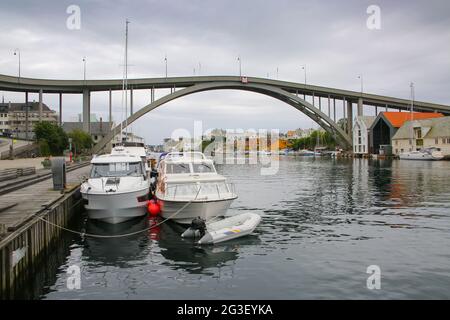 Risoy Brücke über den Fluss im Zentrum der Stadt. Umgeben von traditionellen Gebäuden und Booten im Wasser, Haugesund, Norwegen. Stockfoto