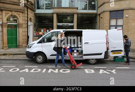 Die Freiwilligen Michelle und Paul laden einen Lieferwagen mit Lebensmittelpaketen zur Auslieferung vor das Welcome Center in Huddersfield in West Yorkshire. Die Welcom Stockfoto