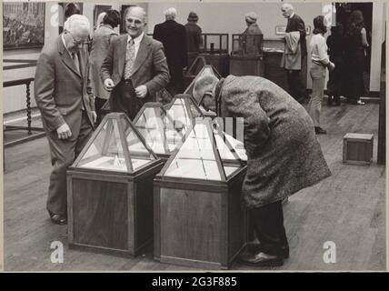 Drei Männer betrachten Spiegelanordnungen in pyramidenförmigen Vitrinen; Anamorphosen. . Stockfoto