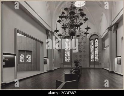 Heregaller in südlicher Richtung mit Kirchenfenstern, Besucherbänken, einem Kronleuchter und Schränken; Ausstellung Französische Kirchenfenster. An der Rückwand sind die Werke der Barmherzigkeit von Engrand und Jean Le Prince aus der Kirche Saint-Vincent in Rouen ausgestellt. Die beiden Fenster auf der rechten Seite sind Szenen aus dem Martyrium des heiligen Vincentius, aus derselben Kirche. Im Kabinett auf der linken Seite sehen Sie vier Sybillen, die Geburt Christi, die sichtbar verkündet wird, aus der Pfarrkirche von Montfey (Aube). Stockfoto