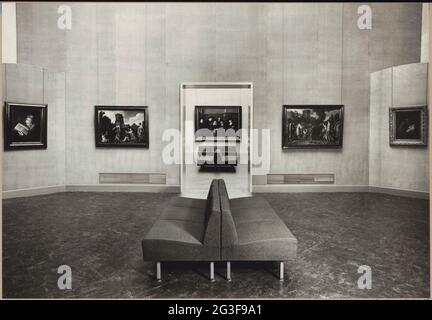 Raum mit Gemälden, Durchgang mit Blick auf die Stahlmeister und eine Bank für Besucher; Sanierungshallen 1958. Links an die schräge Wand in Raum 220 hängen die alte Frau, die in einem lectionarium (angeblich Porträt von Rembrandts Mutter) von Gerard Dou liest. Rembrandts Hand Stahl Meister. Stockfoto