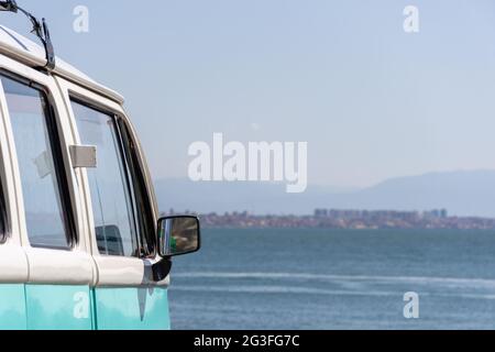 Nahaufnahme des türkisfarbenen Volkswagen-Van, der in der Nähe des Strandes geparkt ist, Sommerferienkonzept. Stockfoto