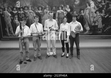 Fünf Musiker posieren mit ihrem Blasinstrument für ein Gemälde; Music Weekend. Links hängt von "Offizieren und anderen Schützen des Viertels VIII in Amsterdam unter der Leitung von Kapitän Roelof Bicker und Leutnant Jan Michielsz Blauw", von Bartholomeus van der Helst ab. Stockfoto