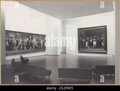 Nachtsaal mit zwei Gemälden; Abteilung für Innenmalerei im Jahr 1959. Nacht vandelzaal im Südwesten gesehen. Auf der rechten Seite der Westwand die Nachtwache und Links zur Südwand "Offiziere und andere Schützen des VIII. Bezirks in Amsterdam von Kapitän Roelof Bicker und Leutnant Jan Michielsz Blauw" von Bartholomeus van de Brost geführt. Fünf Banken stehen im Vordergrund. Stockfoto