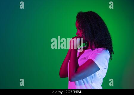 Ernst. Latino-Frauenporträt isoliert auf Studiohintergrund in Neon. Schönes weibliches Modell. Stockfoto