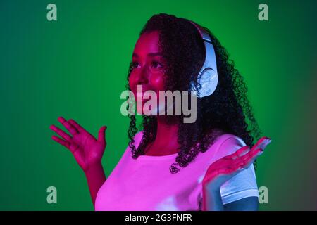 Latino-Porträt einer jungen Frau auf dunklem Studiohintergrund in Neon. Konzept der menschlichen Emotionen, Gesichtsausdruck. Stockfoto