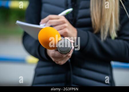Journalistin bei Pressekonferenz, Schreiben von Notizen, mit Mikrofon Stockfoto