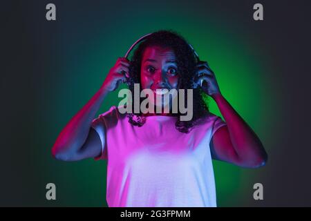 Latino-Porträt einer jungen Frau auf dunklem Studiohintergrund in Neon. Konzept der menschlichen Emotionen, Gesichtsausdruck. Stockfoto