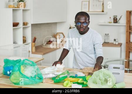 Afrikanischer junger Mann, der den Müll in der Küche zu Hause sortiert Stockfoto