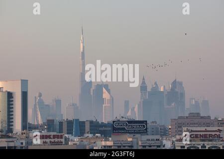 Die Skyline in der Abenddämmerung des Geschäftsviertels von Dubai, den Vereinigten Arabischen Emiraten, mit dem Burj Khalifa, dem höchsten Gebäude der Welt und einer Vogelschar am Himmel Stockfoto