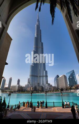 Blick auf das höchste Gebäude der Welt, den Burj Khalifa in Dubai, den Vereinigten Arabischen Emiraten. Hohe Torbögen und Menschen mit blauem Himmel Hintergrund. Stockfoto