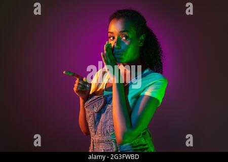 Latino-Porträt einer jungen Frau auf dunklem Studiohintergrund in Neon. Konzept der menschlichen Emotionen, Gesichtsausdruck. Stockfoto