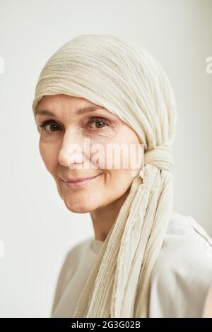 Minimalistisches Kopfbild einer schönen reifen Frau, die Kopftuch trägt und die Kamera anschaut Stockfoto