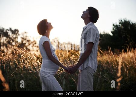 Schwanger mit Ehemann auf Wiese bei Sonnenuntergang Stockfoto