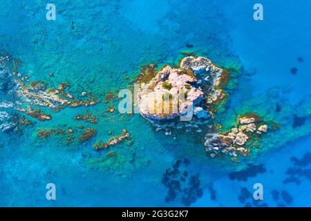 Insel und flaches Wasser im Blauen Ozean. Scharfe Klippe aus Stein. Felsiges Riff mit türkisfarbenem Wasser, Meereswellen am wunderschönen Strand Luftaufnahme Drohne geschossen, Stockfoto