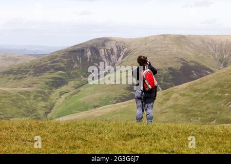 Frau fotografiert von Arant Haw im Yorkshire Dales National Park. Sie blickt auf nahe gelegene Hügel. Stockfoto