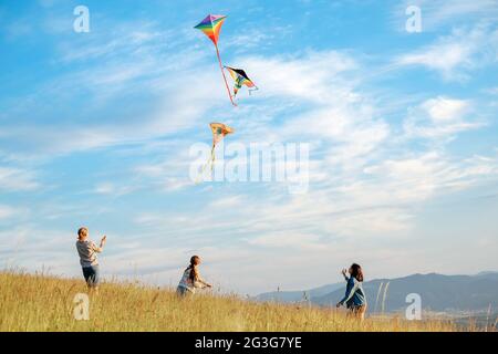 Kinder Drachen kämpfen mit fliegenden bunten Drachen - beliebtes Outdoor-Spielzeug auf der Hochgrasbergwiese. Glückliche Kindheitsmomente oder Outdoor-Zeit spe Stockfoto